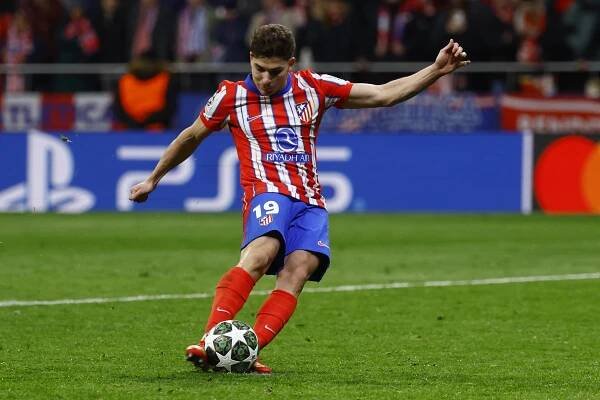 Atletico Madrid player kicking a soccer ball.