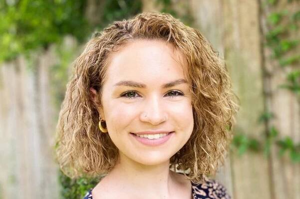 A woman with curly hair wearing a leopard print shirt.