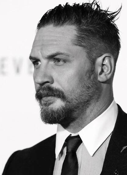 a black and white photo of a man with a beard wearing a suit and tie