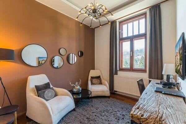 a living room with a table and chairs and a chandelier at Wellness & spa hotel Augustiniánský dům in Luhačovice
