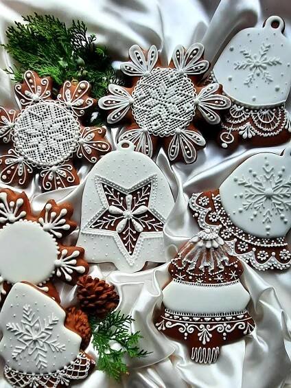 christmas cookies decorated with white icing and snowflakes are on a satin tablecloth