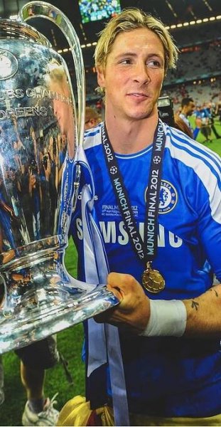 a man holding a trophy in front of his face with other people behind him on the field