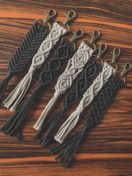 four crocheted key fobs are shown on a wooden surface, one is black and the other is white