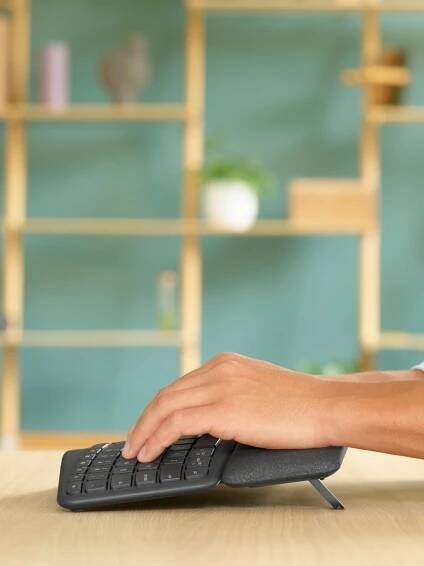 Ruce píšící na zakřivené ergonomické klávesnici