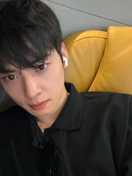 a young man with ear buds on his ears is sitting in a chair and looking at the camera