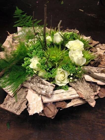 a bouquet of white flowers sitting on top of a pile of wood