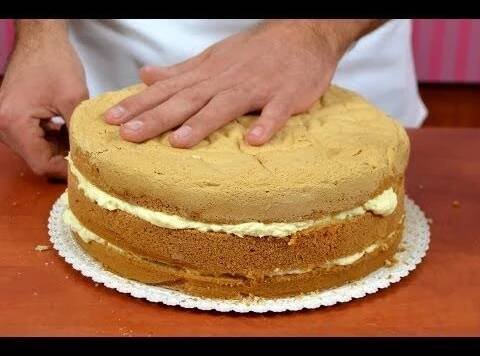 a person cutting into a cake on top of a wooden table