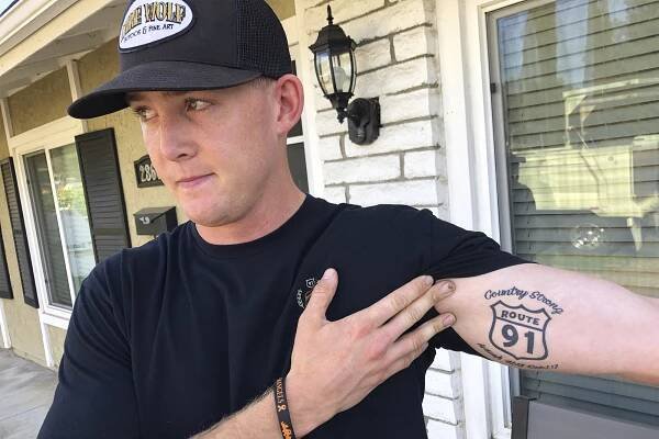 Brendan Kelly shows his Route 91 tattoo to reporters.