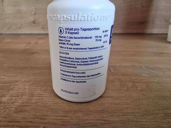Eisenpräparat im Test: weißer Kunststoffbehälter mit Produktinformationen auf einer Holzfläche.