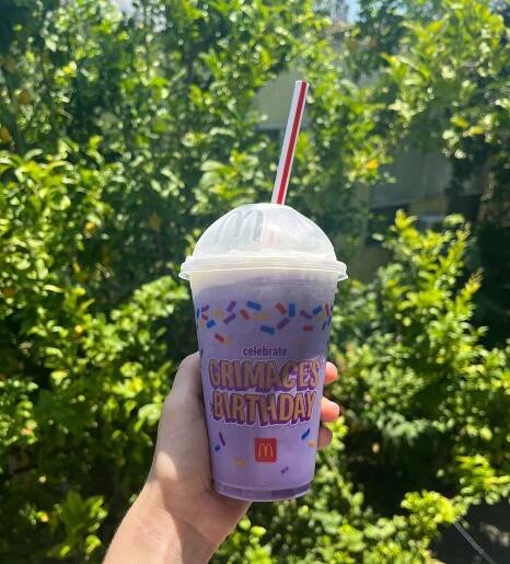 Holding McDonald's Grimace shake in front of greenery