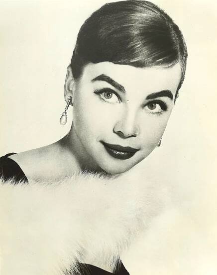 Head shot of Leslie Caron wearing white fur scarf and pearl earrings