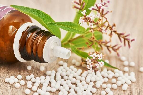 Homeopatických granulí roztroušených na dřevěný stůl — Stock obrázek