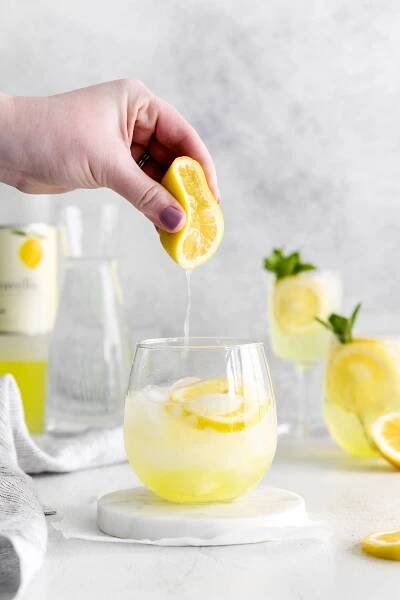 lemon being squeezed to make a limoncello spritz