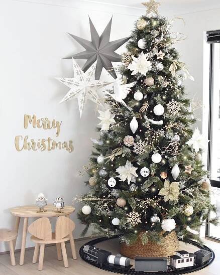 a decorated christmas tree in a living room with white and silver decorations on the top