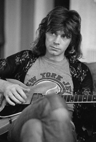 Dave Edmunds wearing a New York Jets shirt and playing an electric guitar.