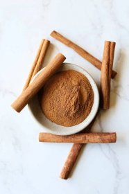 Cinnamon substitute with ground cinnamon and cinnamon sticks on a counter.