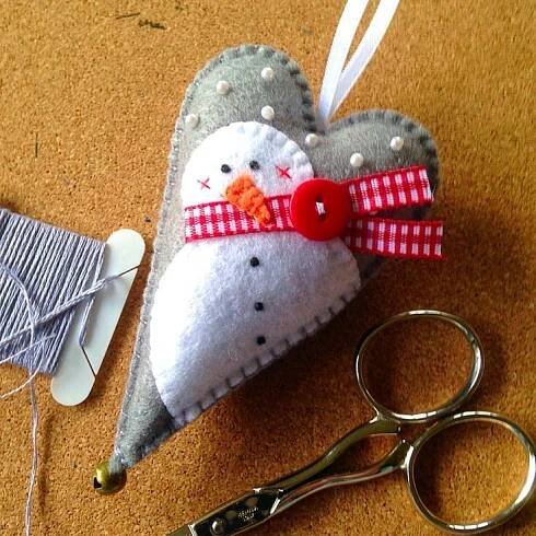 a heart shaped ornament sitting on top of a table next to scissors and thread