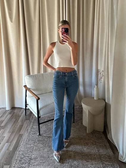 Women trying on Abercrombie bootcut Jeans in front of a chair and table