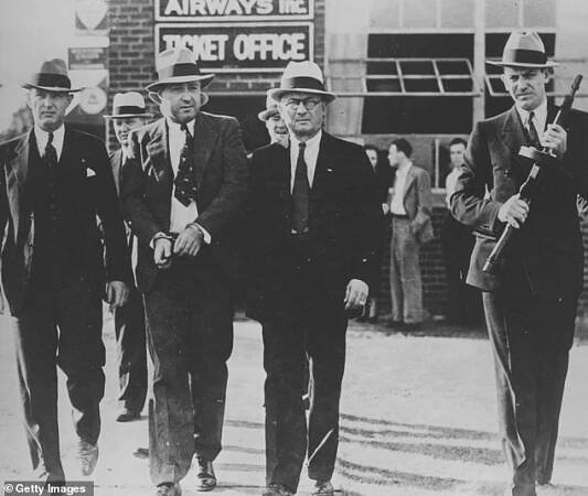 George Kelly is led away in handcuffs by FBI agents after his arrest