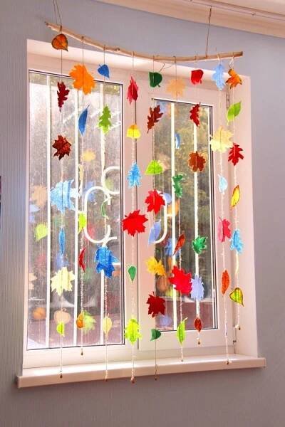 the window is decorated with colorful autumn leaves and ribbons hanging from it's sides