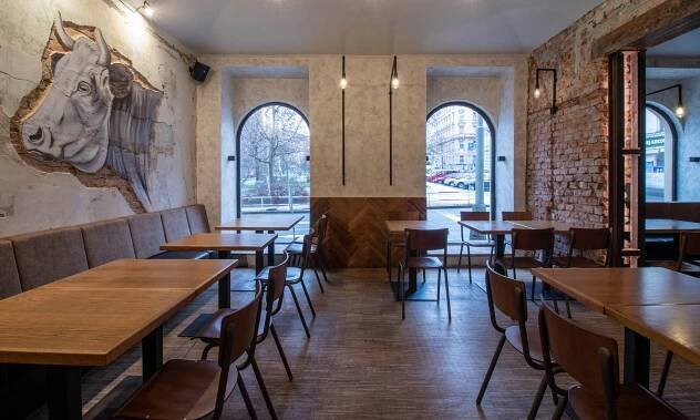 Pražská restaurace Kravín má surový industriální interiér s malbami skotu na otlučených stěnách – DesignMag.cz