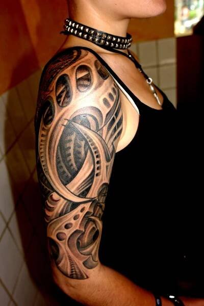 a woman with a black and grey tattoo on her arm is looking at the camera