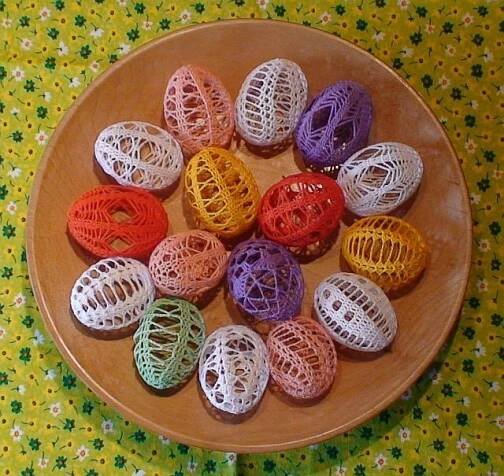 there are many crocheted eggs in the bowl on this tableclothed surface