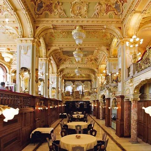Von Helsinki bis Neapel: Café New York, Budapest Zu den prunkvollsten Kaffeehäusern Budapests zählt das 1894 eröffnete Café New York. Zu Beginn der 1890er Jahre ließ die New York Life Insurance Company am Budapester Großen Ring ein aufwendiges Gebäude durch den Architekten Alajos Hauszmann errichten. Das Café wurde schließlich im Jahr 1894 eröffnet und überdauerte Kriege und Regimewechsel weitestgehend unbeschadet bis heute. Es befindet sich im Erd- und Untergeschoss und ist mit üppigem Dekor ausgestattet, das stark an Kirchenräume erinnert.
