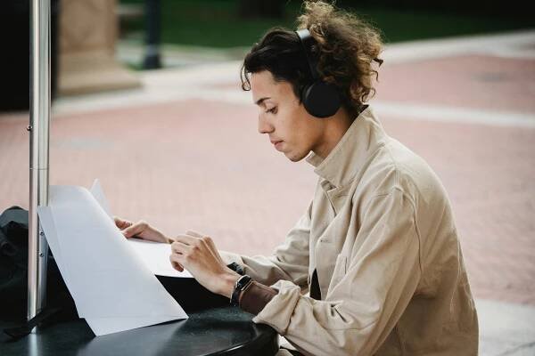 man-writing-on-paper-outdoors-while-listening-to-music-self-care-checklist