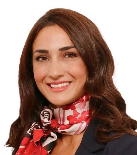 Porträt von Simona Zarbo, verantwortlich für das Praxismanagement, mit rot-gemustertem Halstuch und freundlichem Lächeln.