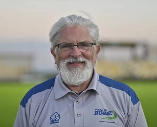 A man with a beard and glasses is wearing a rugby shirt