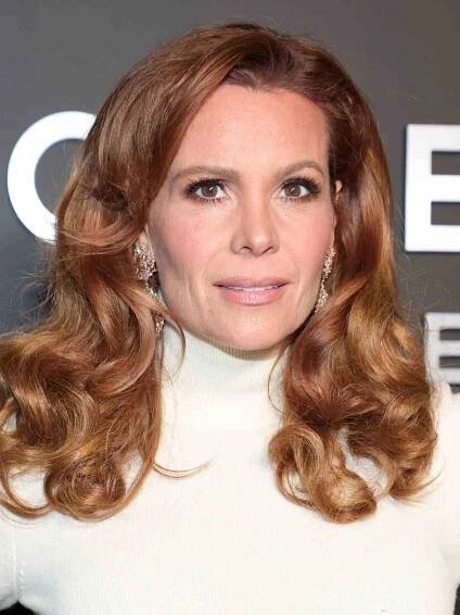 Robyn Lively in a white top with curly dark strawberry blonde hair