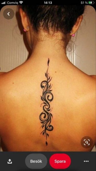 the back of a woman's neck with an intricate tattoo design on her lower back