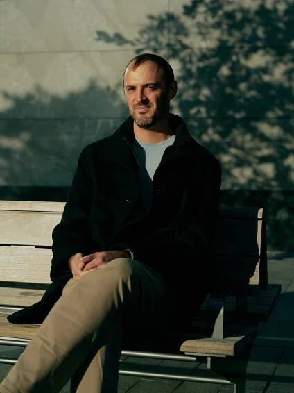 Nathan Anderson sits on an outdoor bench. 