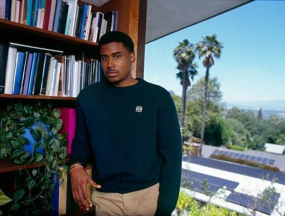 Michael Cooper leans against a bookshelf.
