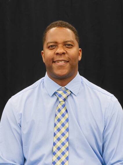 Headshot of President Dr. DJ Washington wearing a light blue shirt and a necktie
