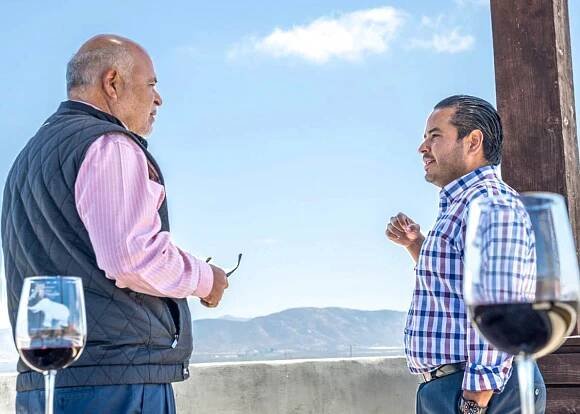 Padre e hijo hablando frente a Valle de Guadalupe.