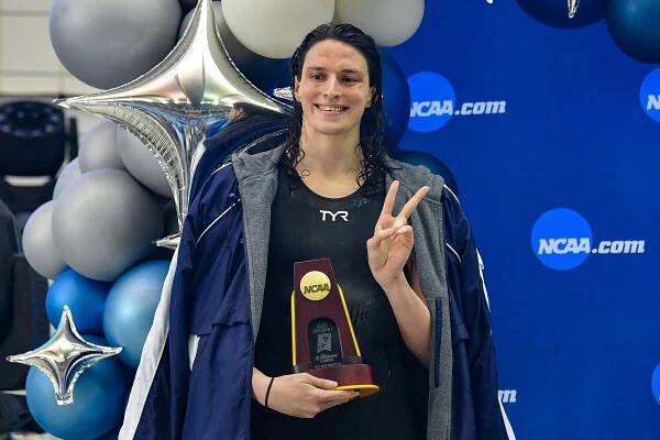 A white woman smiles at the camera and makes a peace sign while holding an award.