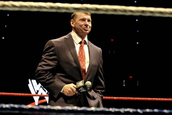 Vince McMahon holding a microphone in a wrestling ring.