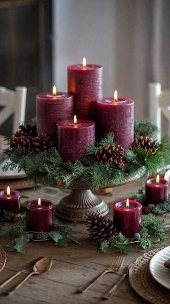a table topped with lots of candles next to pine cones and greenery on top of plates