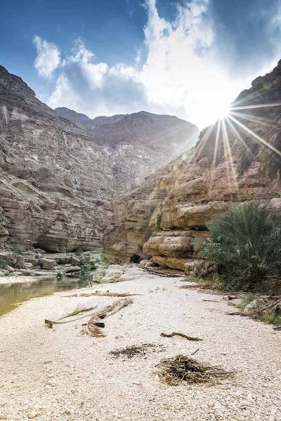 Sun Peaking through the mountains at Wadi Shab Oman -  The Travel Escape