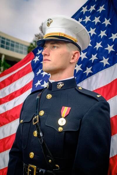 A United States Marine poses for a portrait in front of a USA flag on the University of Florida Campus.
