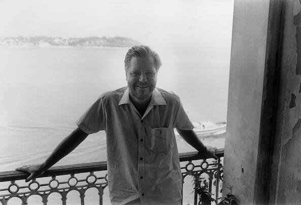 Gerald Durrell posing on balcony in front of water