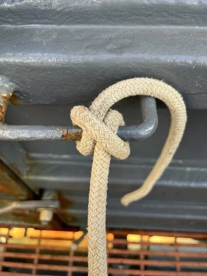 close-up of a rope tied to a metal hook in a clove-hitch; hard to see where this is located