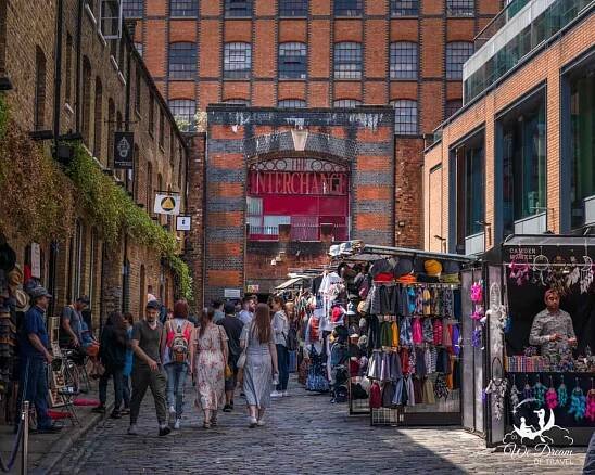 Camden Market lined with stalls and crowds of people walking through it.