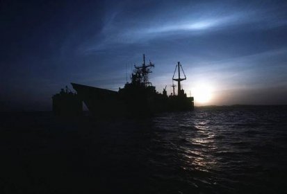 The guided missile frigate USS SAMUEL B. ROBERTS (FFG-58) is silhouetted by the setting sun as it is tranported on the deck of the Dutch heavy-lift ship MIGHT SERVANT II.  The MIGHTY SERVANT is transporting the frigate, which was damaged when it struck an Iranian mine on April 14, 1988, to its home port in Newport, R.I.
