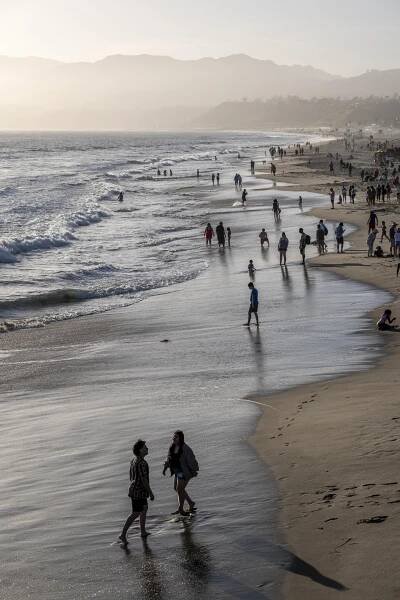 Beachgoers walk along the shore near the Santa Monica Pier.