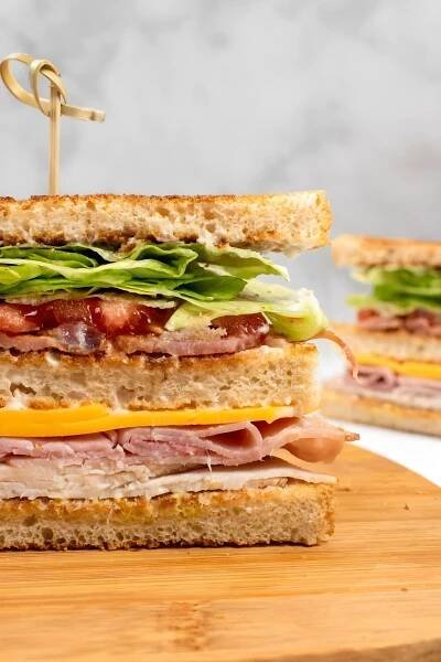 Half of the club sandwich on cutting board.