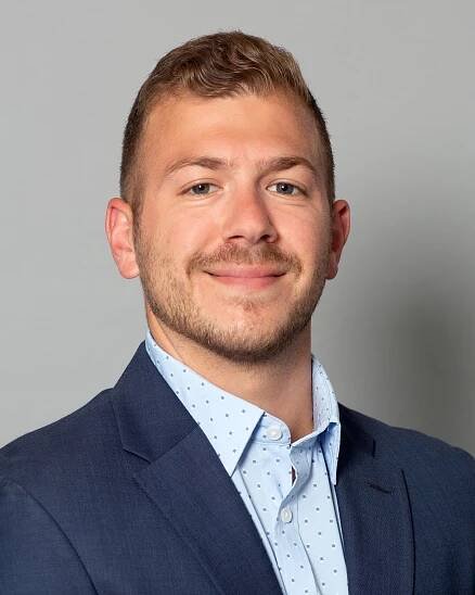 A man in a suit and white shirt is smiling for the camera.