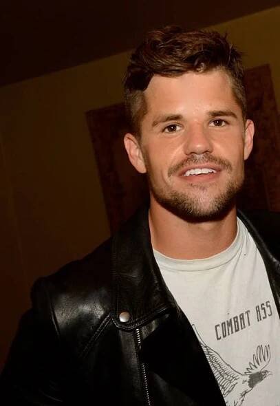 a man in a leather jacket smiling for the camera